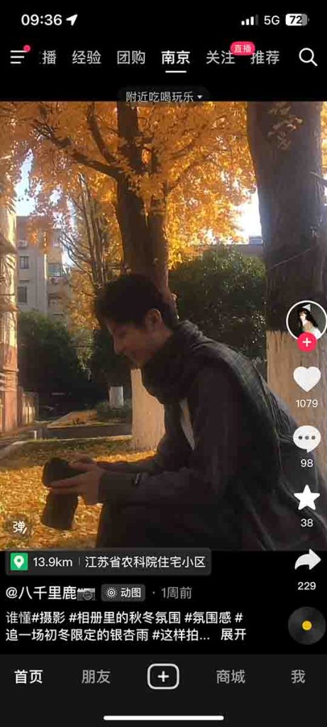 A young Chinese man sitting in a park preparing his camera for a photoshoot.